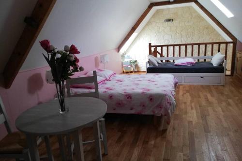 Leschellesles alouettes的一间卧室配有一张床和一张带玫瑰花瓶的桌子