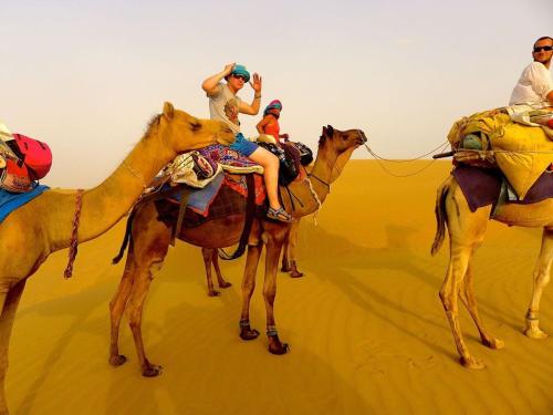 山姆Sky Desert Safari & Spa的一群人骑着骆驼在沙漠中