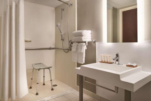 尚佩恩Wyndham Garden Conference Center Champaign - Urbana的浴室配有白色水槽和淋浴。