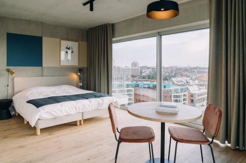 鲁汶De Hoorn的一间卧室配有一张床、一张桌子和一个窗户。