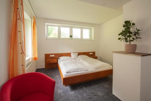 比尔塞贝格加尼碧姬酒店的一间卧室配有一张床和一张红色椅子