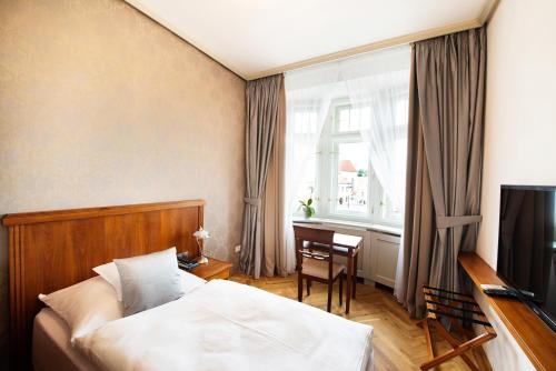 佩尔赫日莫夫Hotel Slávie Pelhřimov的一间卧室配有一张床、一张书桌和一台电视