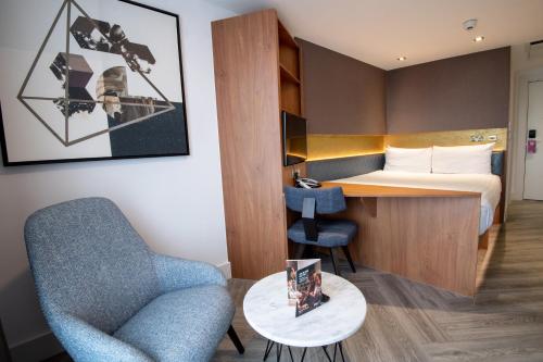 伦敦伦敦斯特拉福德隆姆茨公寓式酒店的酒店客房配有一张床、一把椅子和一张书桌