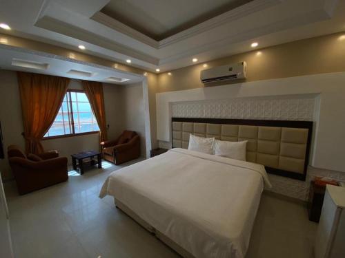 Ḩilf达纳阿尔卡勒酒店的卧室配有一张白色大床和两把椅子