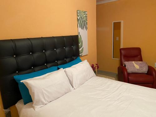 波罗瓜尼Mankweng lodge的一间卧室配有一张带黑色床头板和红色椅子的床