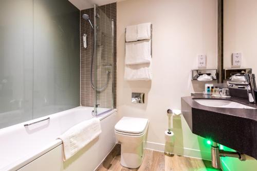 朗科恩朗科恩M56高速公路12号交叉口假日酒店的浴室配有卫生间、盥洗盆和浴缸。
