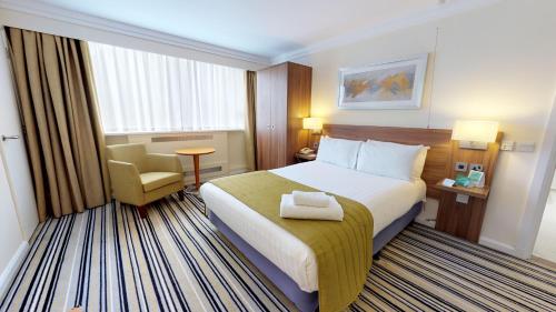 朗科恩朗科恩M56高速公路12号交叉口假日酒店的配有一张床和一把椅子的酒店客房