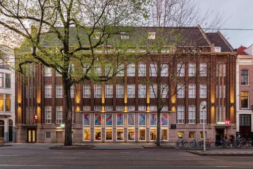 阿姆斯特丹citizenM Amstel Amsterdam的前面有树木的大型砖砌建筑