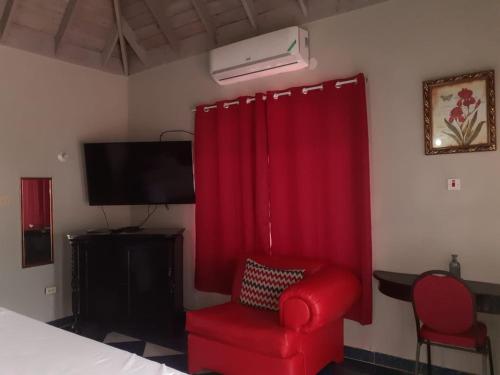 蒙特哥贝Jobs Inn Jamaica的一间带红色椅子和电视的卧室