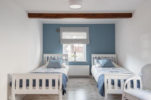 亚斯塔尔尼亚PATYKIEM PO WODZIE的蓝色墙壁客房的两张床