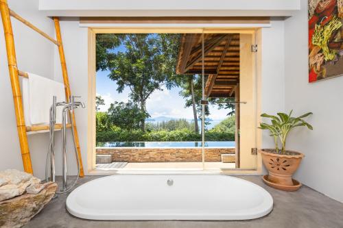 阁遥岛SAMSAM Yao Noi - ANDAMAN MAGIC & ART VILLAS的带窗户的浴室内的白色大浴缸