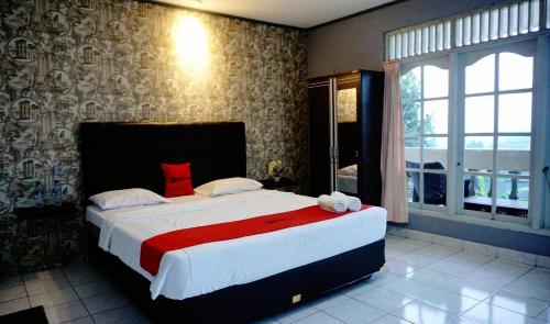 茂物Residences by RedDoorz near Taman Safari的一间卧室配有一张带红色毯子的大床