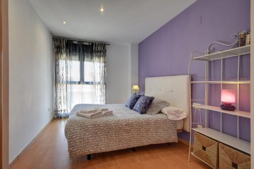 瓦伦西亚Malvarrosa Beach Apartment的一间卧室配有一张床和紫色的墙壁
