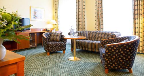格拉Victor's Residenz-Hotel Gera的酒店客房设有沙发、桌子和椅子。