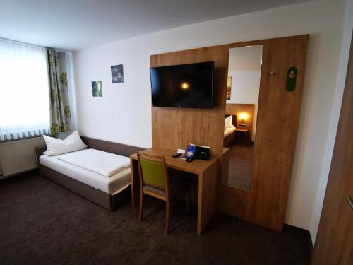 阿勒斯贝格Gasthof Endres的酒店客房配有书桌、床和电视。