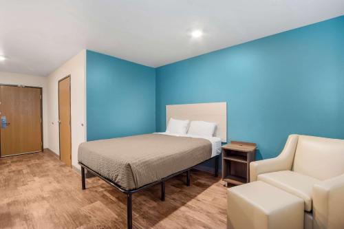 查尔斯顿WoodSpring Suites | North Charleston Airport I-526的一间卧室配有一张床、一张沙发和一把椅子
