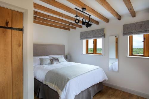 阿什比德拉祖什Hastings Retreat Rural barn conversions with Private Lake的一间卧室配有一张带白色床单和窗户的床。