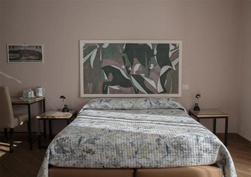 那不勒斯B&B Galleria Principe di Napoli的卧室配有一张床,墙上挂有绘画作品