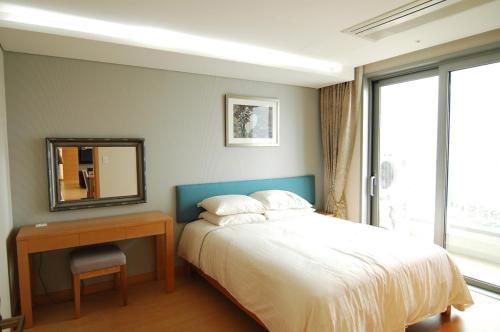 西归浦市Keumho Jeju Resort的一间卧室配有一张床、一张桌子和一面镜子
