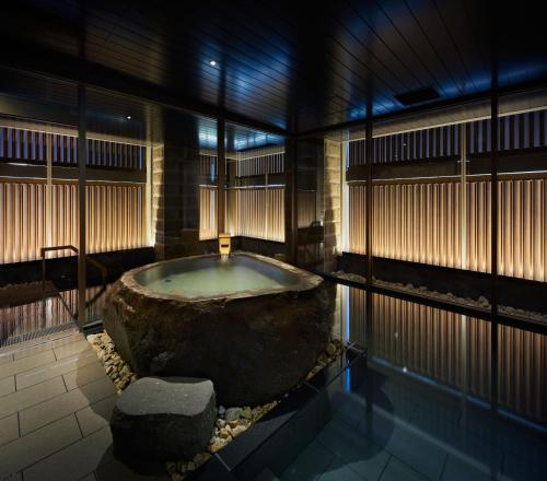 札幌ONSEN RYOKAN Yuen Sapporo的一个大浴缸,位于一个大岩石的房间