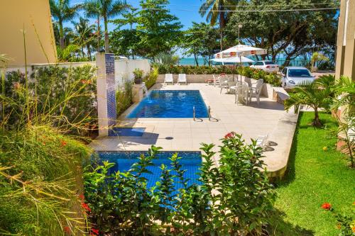 塞古罗港Quinta do Sol Lite Praia Hotel的庭院内的游泳池配有椅子和遮阳伞