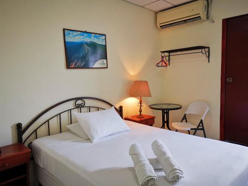 圣萨尔瓦多Hotel Armonía Hostal的卧室配有白色的床和2条毛巾