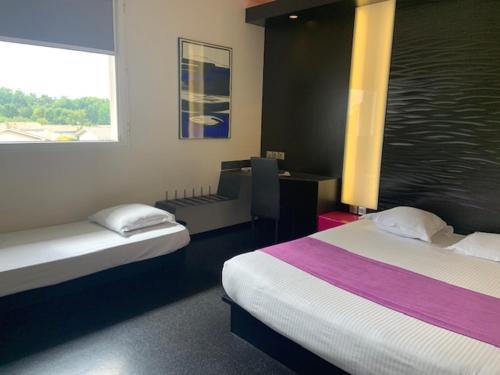 Yvrac波尔多东卡迪尼亚酒店的客房设有两张床和一张带窗户的书桌。