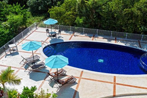 恩纳Odysis Onna Resort Hotel的游泳池旁设有椅子和遮阳伞