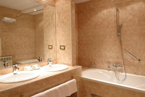 萨格勒布AS酒店的浴室配有2个盥洗盆、浴缸和淋浴。