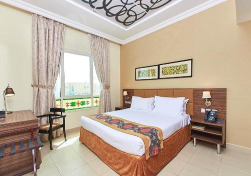 拉斯阿尔卡麦Mughal Suites的一间卧室配有一张床、一张书桌和一个窗户。