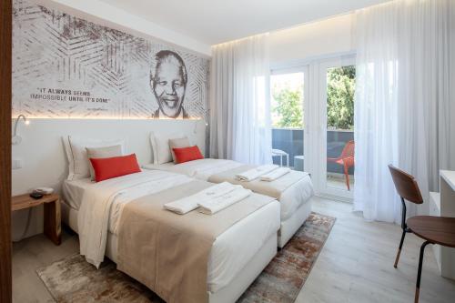 里斯本The ICONS Lisbon Central Hotel的白色客房的两张床,设有大窗户