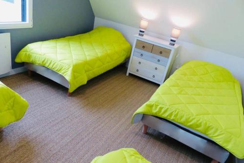提赫嘎它尔Maison avec SPA côte de granit rose的一间卧室设有两张床和一张黄色床单的梳妆台。