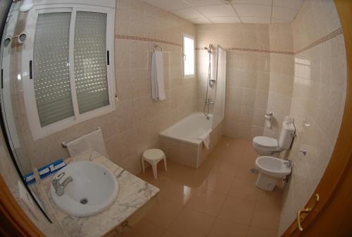 普拉森西亚Hotel Dora的一间带水槽、浴缸和卫生间的浴室