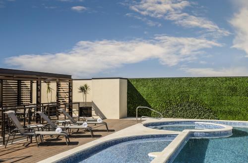 克雷塔罗Fiesta Inn Express Queretaro Constituyentes的一个带游泳池和椅子的庭院和一个带围栏的庭院