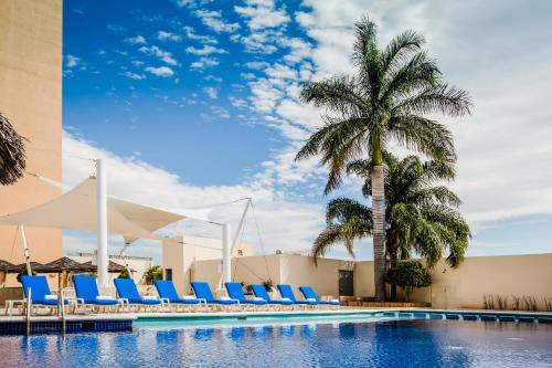 图斯特拉古铁雷斯图斯特拉 - 古铁雷斯费斯塔客栈酒店的一个带蓝色躺椅的游泳池,并种植了棕榈树