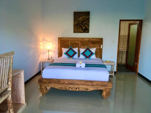 艾湄湾Agung Inn Amed的一间卧室配有一张大床和木制床头板