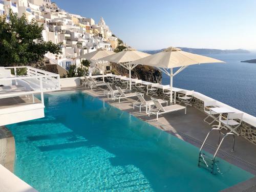 费拉Panorama Suites的一个带椅子和遮阳伞的游泳池以及大海