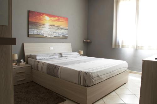 圣特雷莎加卢拉Condominio Le Palme的卧室配有一张床,墙上挂有绘画作品