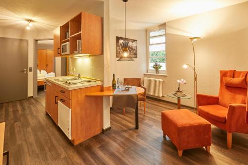 欣特察尔滕贝弗雷德公寓式酒店的厨房以及带桌椅的起居室。