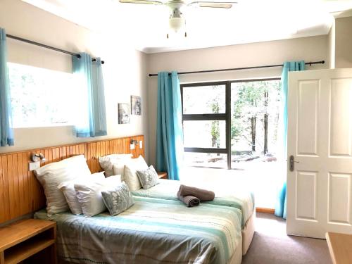 温特顿Berghaven Cottages的一间卧室配有一张带蓝色窗帘的床和一扇窗户