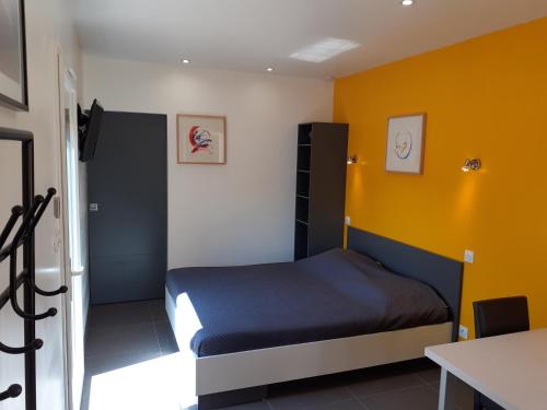 屈屈尼昂Studio les trois chemins的一间卧室设有一张床和黄色的墙壁