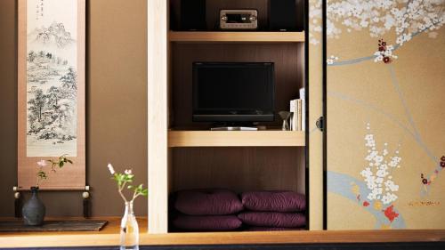 京都Kokonoe Machiya的一个带电视及紫色靠垫的橱柜