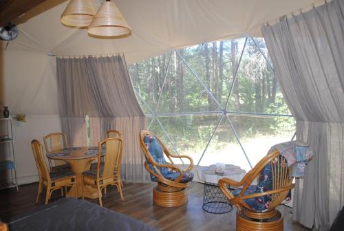 苏普拉希尔Glamping Drzwi Do Lasu的客房设有桌椅和大窗户。