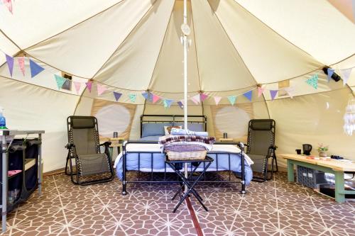 Little HautboisPitch Perfect Glamping Norfolk的帐篷内的卧室,配有一张床和两把椅子