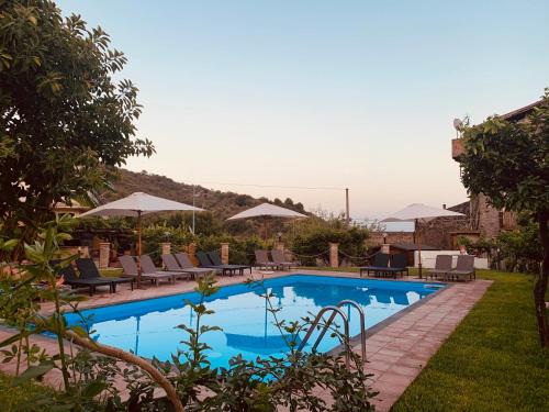 莫塔卡玛斯特拉Villa Le Gemelle Dell'Alcantara的度假村内带椅子和遮阳伞的游泳池