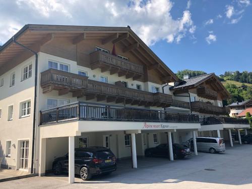 卡普伦AlpinResort Kaprun 2的停车场内停放汽车的大型建筑