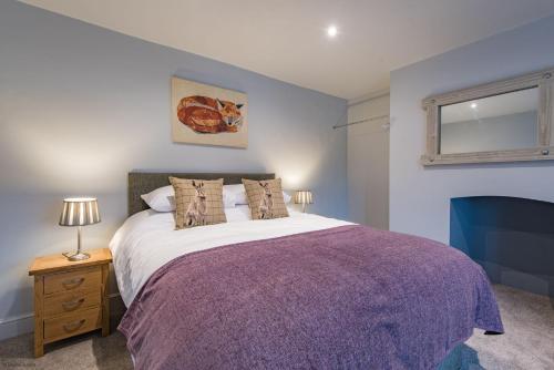 法弗舍姆Customs House by Bloom Stays的一间卧室配有一张大床和紫色毯子
