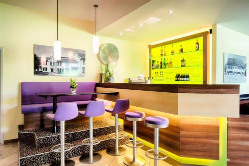 茨维考ACHAT Hotel Zwickau的酒吧,带紫色凳子和桌子