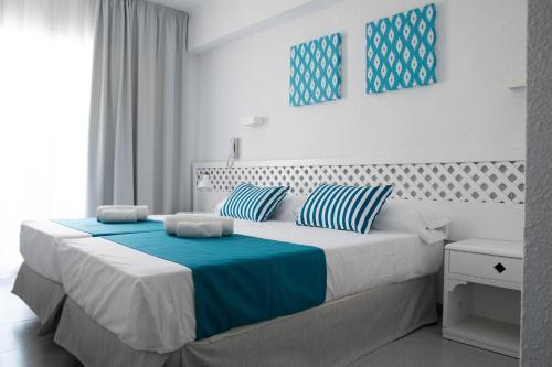 埃尔阿雷纳尔BLUESEA Mediodia的一间卧室配有一张带蓝白色枕头的大床