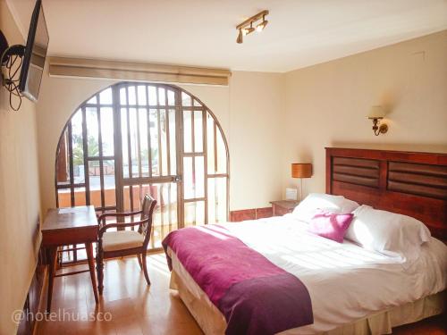 瓦斯科Hotel Huasco的一间卧室配有一张床、一张桌子和一个窗户。